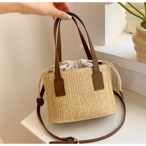 Detail of woven straw handbag featuring brown leather handles and a canvas drawstring liner