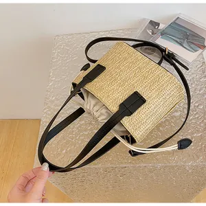 Detail of woven straw bag with black faux leather handles and beige drawstring liner