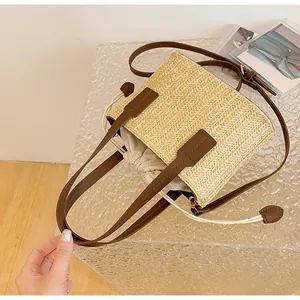 Close-up of straw bucket bag with brown leather handles and secure drawstring liner