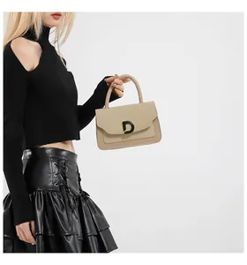 Detail of a beige woven and khaki leather handbag featuring a bold metal D buckle