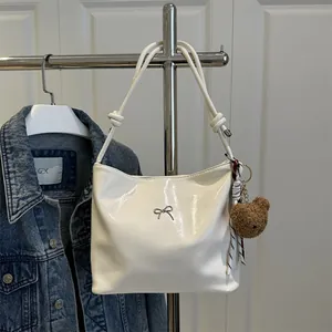 Elegant cream white glossy shoulder bag with bow detail and cute bear keychain charm