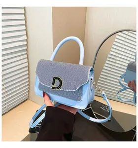 Detail of light blue crossbody bag with denim texture and gold D-shaped buckle
