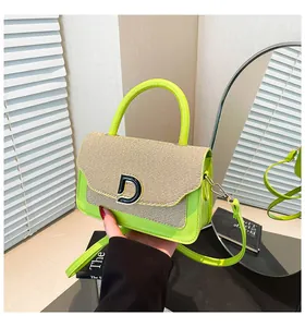 Detail of green straw patchwork crossbody bag with metallic D-logo and top handle