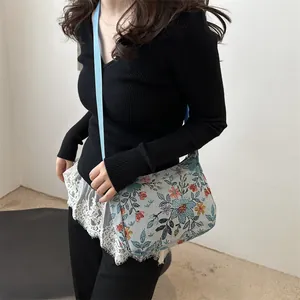 Floral tapestry crossbody tote bag with blue nylon strap shown on a model