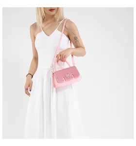 Detail of pink leather handbag showing sequined flap and gold metal letter M logo buckle