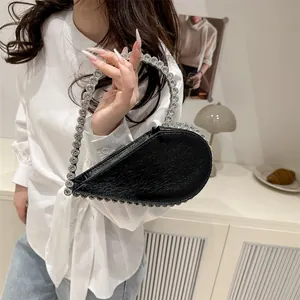Fashionable black heart-shaped handbag with rhinestone handle shown in a modern interior