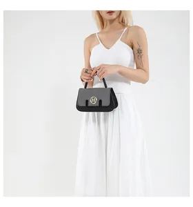 Detail of grey and black patchwork handbag with gold M-logo buckle on white dress