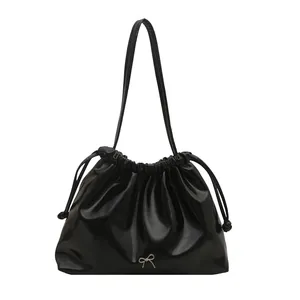 Fashionable black glossy leather drawstring bucket bag with silver bow ornament