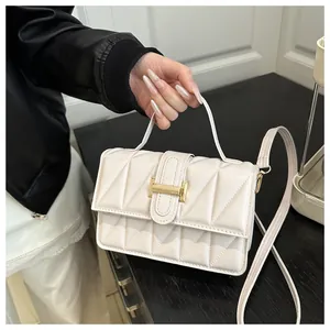 Detail der cremefarbenen Stepptasche mit Rautenmuster und goldenem Metallverschluss