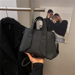 Black striped woven tote bag with top handles and adjustable shoulder strap for women