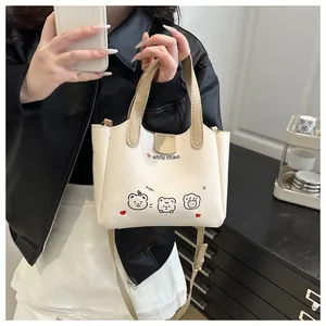 Détail d'un sac cabas en cuir PU blanc crème avec motif ours et poignée kaki clair