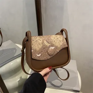 Bolso bandolera vintage de cuero marrón con solapa de jacquard marmoleado en escena