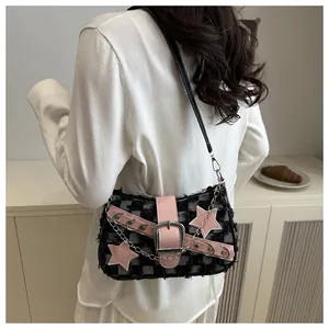Detail van denim schoudertas met roze ster hanger en zilveren metalen gesp