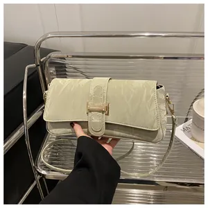 Κοντινό πλάνο πλισέ τσάντας baguette σε φιστικί χρώμα με χρυσή αγκράφα H