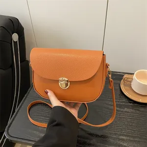 Orange lychee pattern leather saddle bag with gold metal clasp and slim shoulder strap