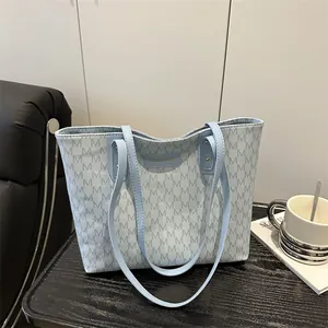 Light blue monogram tote bag with floral patterns and dual shoulder straps in an office setting
