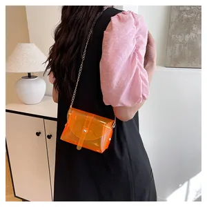 Détail du sac à bandoulière orange jelly avec chaîne dorée sur une tenue de mannequin