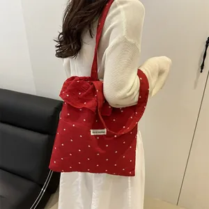 Grand sac cabas rouge à fleurs en résille avec volants porté par un mannequin
