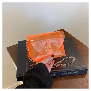 Détail du sac bandoulière orange transparent avec chaîne dorée et fermoir en métal