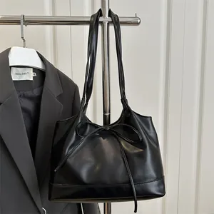 Minimalist black PU leather tote bag with bow detail and large capacity shown on rack