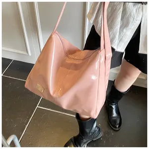 Close-up of pink glossy patent leather tote bag with elegant gold metal logo tag