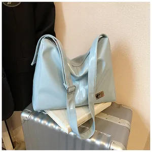 Detail of light blue glossy leather tote bag with silver buckle and metallic logo tag