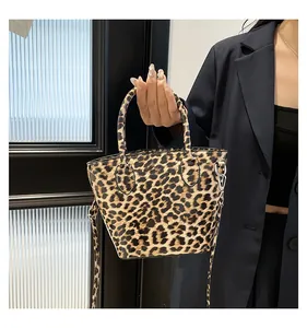 Détail d'un sac à main léopard avec ferrures argentées et bandoulière sur blazer noir