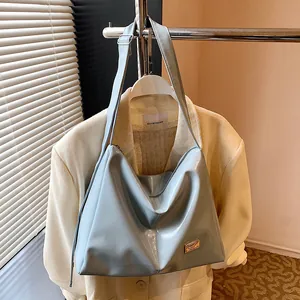 Light blue patent leather hobo bag with gold logo plaque shown in professional studio lighting