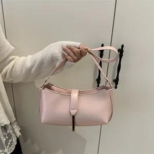 Pink PU leather underarm bag with gold metal buckle held by a model in a minimalist setting