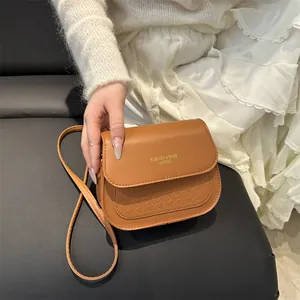 Brown leather crossbody saddle bag with star embossed texture and adjustable strap
