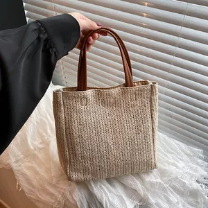 Minimalist straw woven tote bag with brown leather handles and herringbone pattern