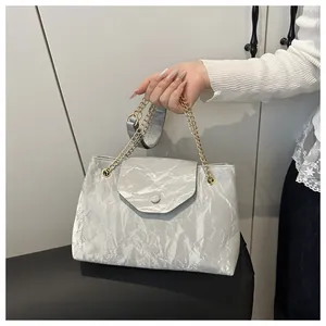 Detail of silver textured tote bag with gold chain strap and pleated metallic finish
