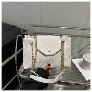 Detail of white wrinkled leather shoulder bag with gold chain strap and magnetic closure