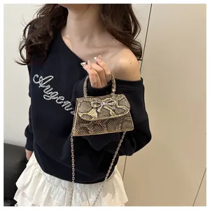 Detail of snake print mini bag with silver bow ornament and metallic chain strap
