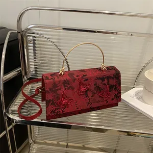 Deep red butterfly embroidered handbag with golden semi-circular handle and shoulder strap