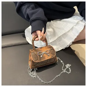 Detail of snake print shoulder bag with silver bow accent and metal chain strap