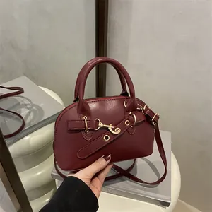 Deep red shell-shaped leather handbag with golden buckle and sleek dual handles