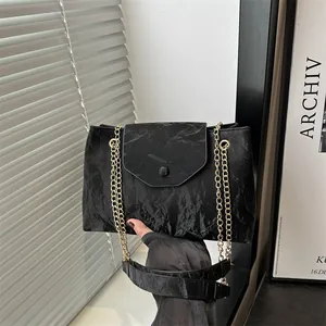 Chic black tote bag with marble texture, gold chain strap and elegant fold-over flap design