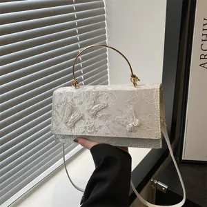 Elegant white lace crossbody bag with butterfly floral embroidery and golden metal handle