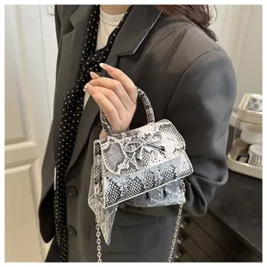 Detail of snake print mini bag with silver bow buckle and white lace fringe charm