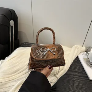 Brown snakeskin crossbody bag with silver bow accent and detachable chain strap