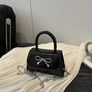 Elegant black crocodile-embossed mini shoulder bag with silver bow detail and chain strap