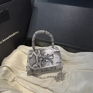 Snake skin pattern crossbody bag with metal bow and silver chain strap on satin