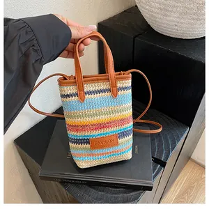 Detail of colorful striped straw bucket bag featuring brown faux leather handles and strap