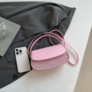 Pink semi-circle crossbody bag with glitter patchwork and golden brand logo detail