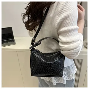 Détail d'un sac bandoulière en cuir tressé noir avec bandoulière et fermeture éclair