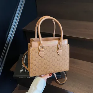 Brown monogram tote bag with top handles and shoulder strap on wooden background