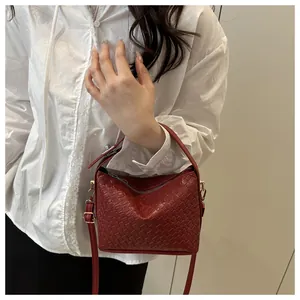 Gros plan du sac bandoulière tressé rouge vin avec texture et détails dorés