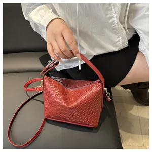 Détail d'un sac à main tissé rouge foncé avec bandoulière réglable et fermeture éclair