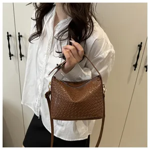 Sac à main marron tissé porté par un mannequin avec bandoulière amovible réglable